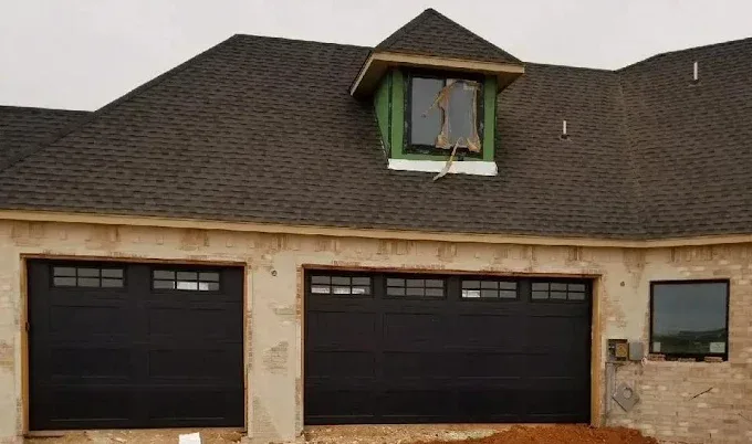 New construction garage door installation with two black doors in Oklahoma City metro by Affordable Door Co